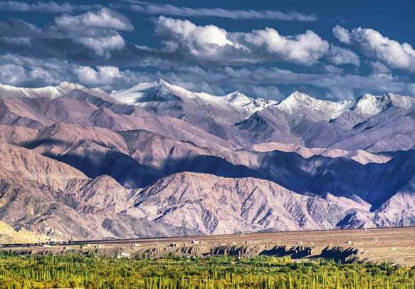 Rocky landscape of with snow peaks at the background at Ladakh
