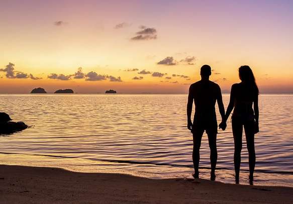 Young couple stay on the beach and watching the sunset on a tropical island Koh Samui