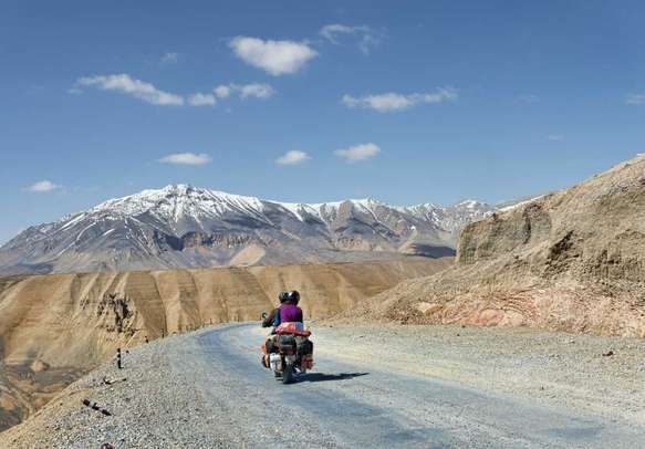 Couple on motorbike riding among mountains