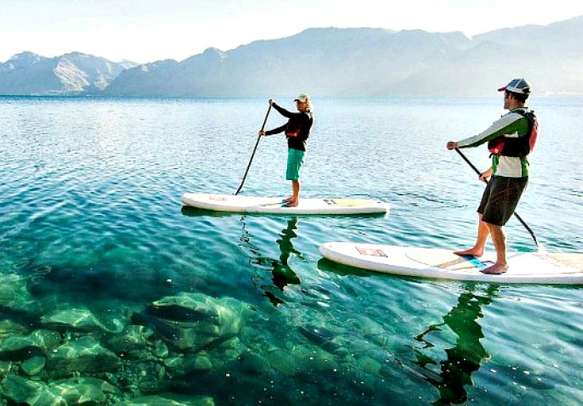 Tourists enjoying paddle boarding in Lake Wanaka