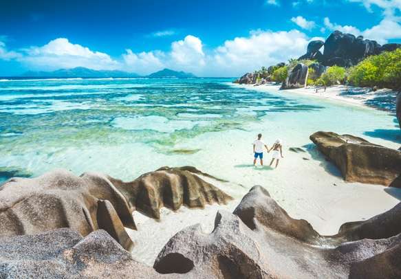 A young couple standing in shallow water on La Digue island