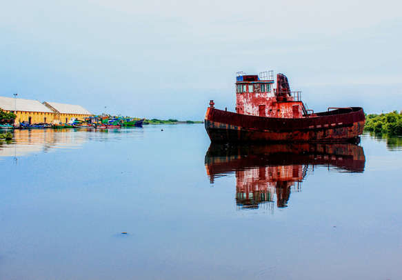 An old red color boat at the backwaters of fishing area in Pondicherry harbor