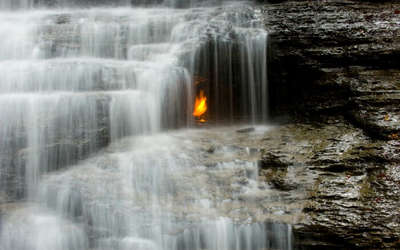 Mysterious eternal flame burning under the waterfall