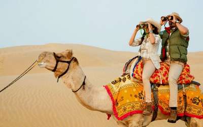 People exploring the vast dunes of desert while enjoying camel safari in Jaisalmer
