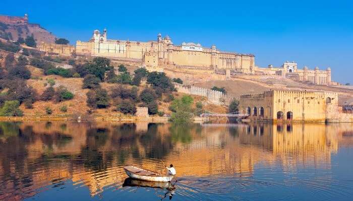 An oarsman rows a boat in the Maota lake in front of Amber fort