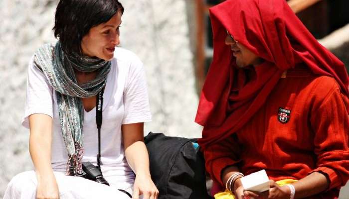 A tourist chatting with a monk at a monastery in Ladakh