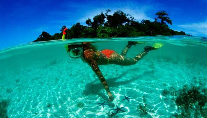 A young girl admiring the rich sea life while snorkeling at Pereybere beach