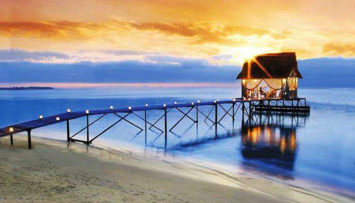 A candle lit pathway leading to an overwater shack, set for a romantic evening at Trou Aux Biches in Mauritius