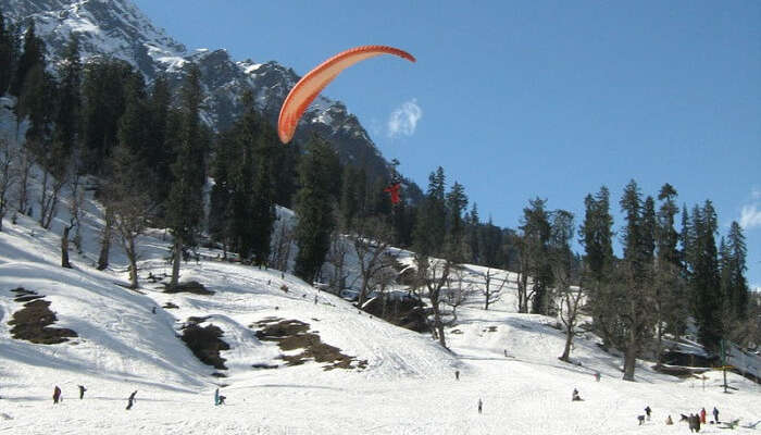 A tourist tries paragliding in the snow-clad Solang valley