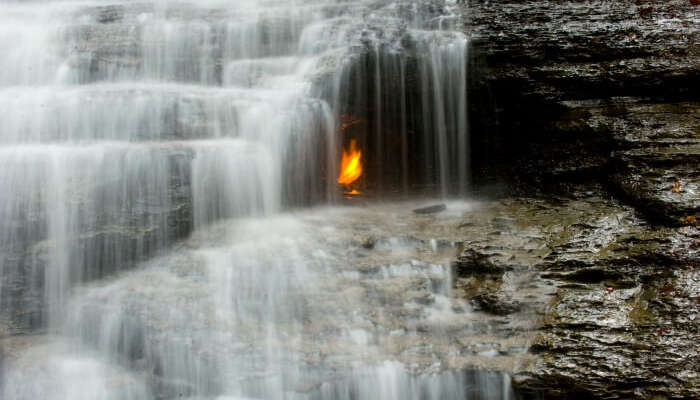 Mysterious eternal flame burning under the waterfall