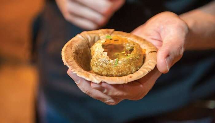 A person holding bowl of Puchka which is a popular street food in Kolkata