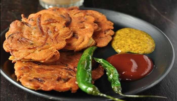 Kolkata Telebhaja served on a plate with chili and sauces