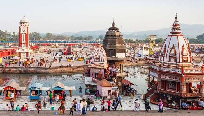 A view of temples by the Ganga river with devotees offering prayers 