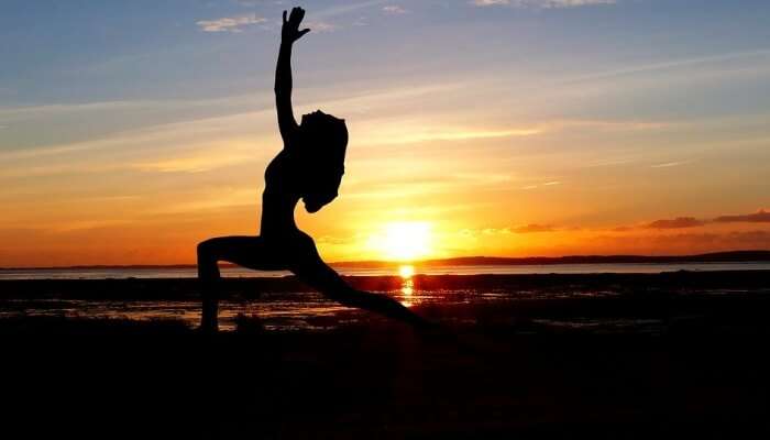 Woman in yoga pose with sunset in the backdrop