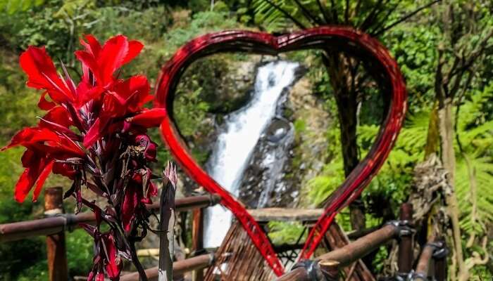 A red heart-shaped frame with Gitgit waterfall