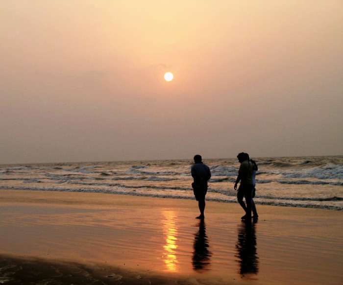Friends enjoying a leisure walk along the beach during sunset