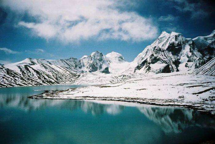 The surrounding snow clad mountains and the crystal clear icy water of Gurudongmar lake in Sikkim