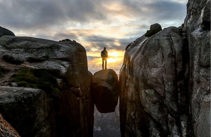 A man poses on the balancing rock 1000 meters above sea level at Kjragbolten in Norway