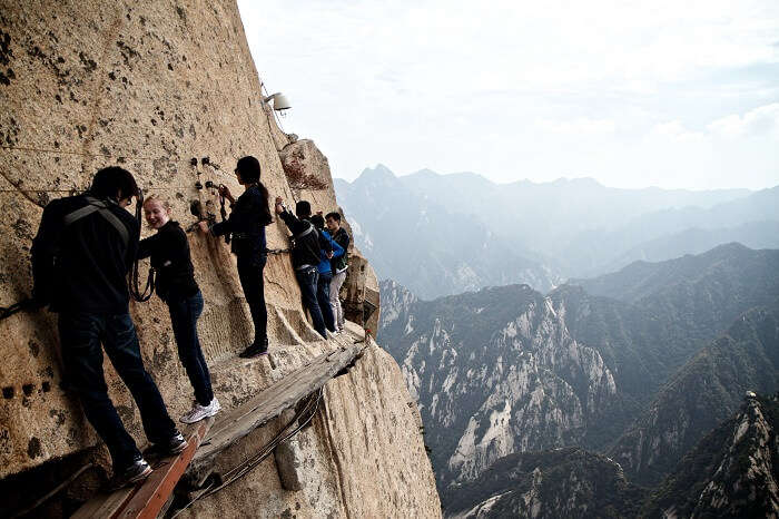Tourists walk on a thin plank at Mount Hua in China