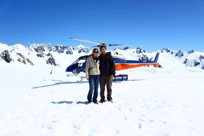 A couple poses with the helicopter used on the heli-hike at Fox Glacier