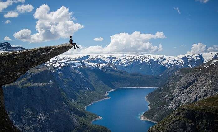 A girl sits at the cliff edge at Trolltunga