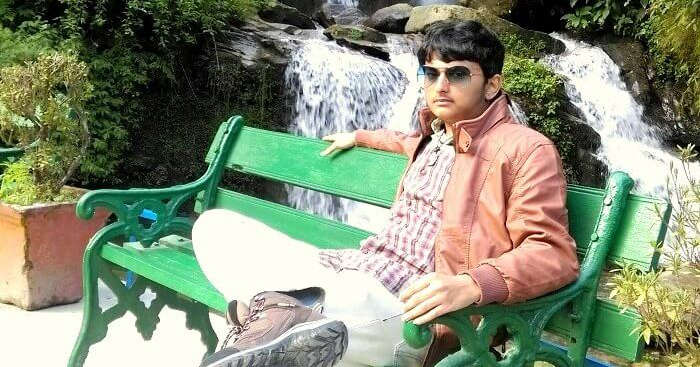 Bala sitting on a bench near a waterfall on his Sikkim-Darjeeling trip