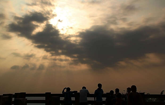 A group gathers to see the sunset at the popular Agumbe Sunset Point in Karnataka