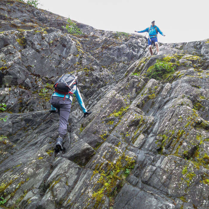 Trekkers rappelling a slippery mountain before reaching the ice cave