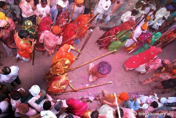 A group of women playfully beating a man with stick during Mathura Holi