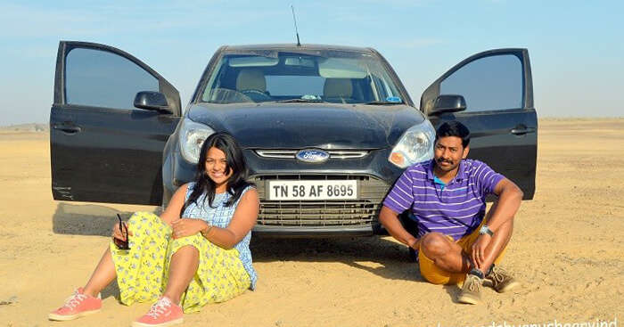 Anusha and Arvind sit outside a Ford Figo in the desert of Pakistan
