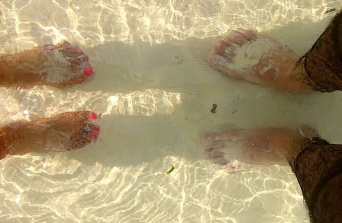 bhinav and his wife's feet immersed in water in Andaman