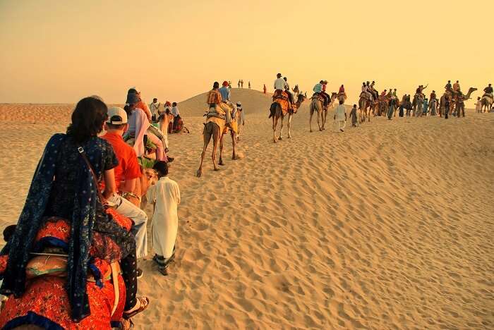 Happy tourists enjoying camel safari in Rajasthan