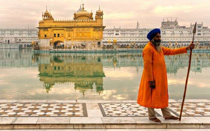 Sikh man standing in front of Golden Temple in Amritsar best place to visit in November in India