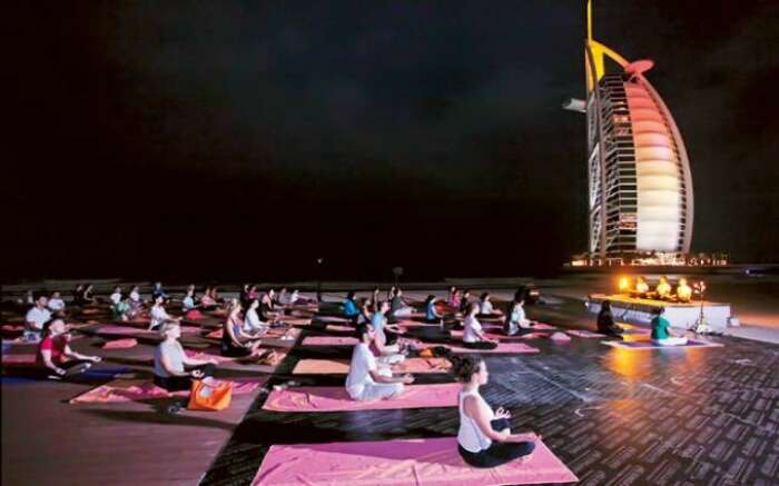 Participants performing Yoga at night with Burj Al Arab in the backdrop