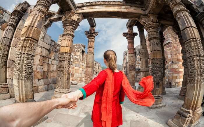 Foreigner at Qutub Minar Delhi wearing a red suit