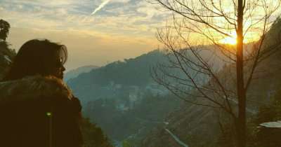 Priyanka standing on a mountain facing sunrise in Mcleodganj