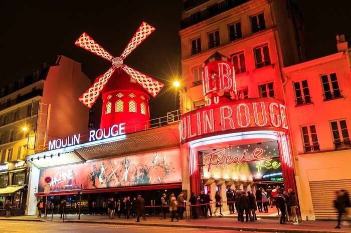 Tourists stand in a queue to enter the Moulin Rouge night cabaret