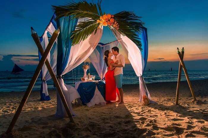 Young beautiful couple have a romantic dinner at sunset on a tropical beach