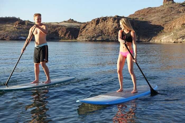 Couple enjoying stand-up paddle boarding on honeymoon