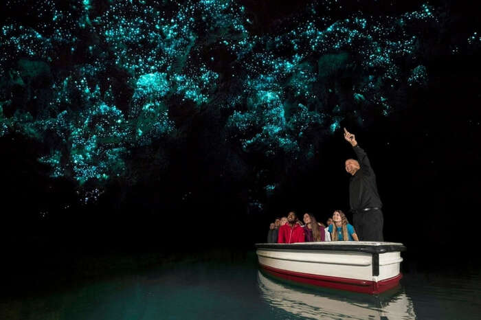 Travelers taking a tour of the Waitomo Glowworm Caves in New Zealand