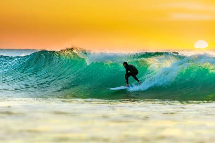 A traveler surfing in Arabian sea near a coast in Kovalam