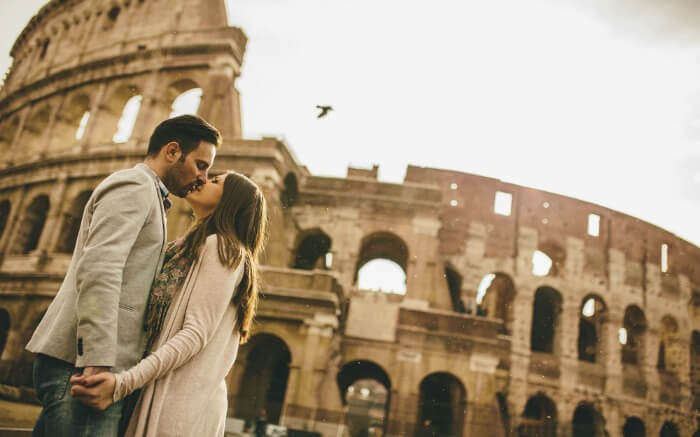 A couple kissing in front of Colosseum