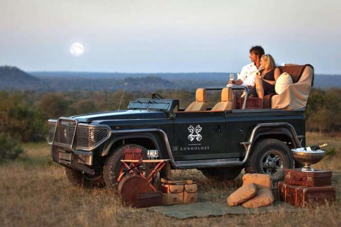 Couple on a gypsy watching sunset during their safari honeymoon in South Africa