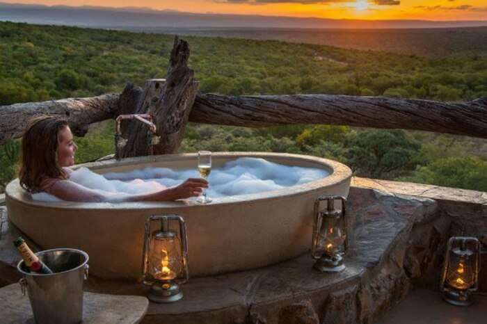 A honeymooner showering in a tub in jungle lodge in South Africa