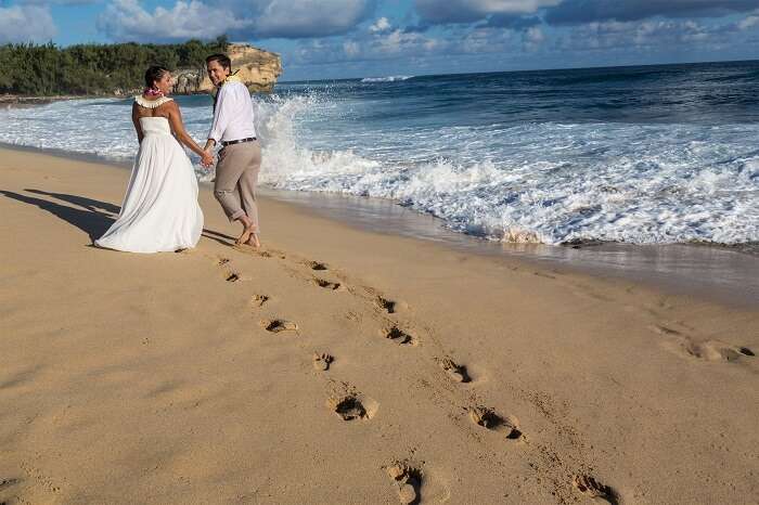 romantic couple walking on the beach in Kauai