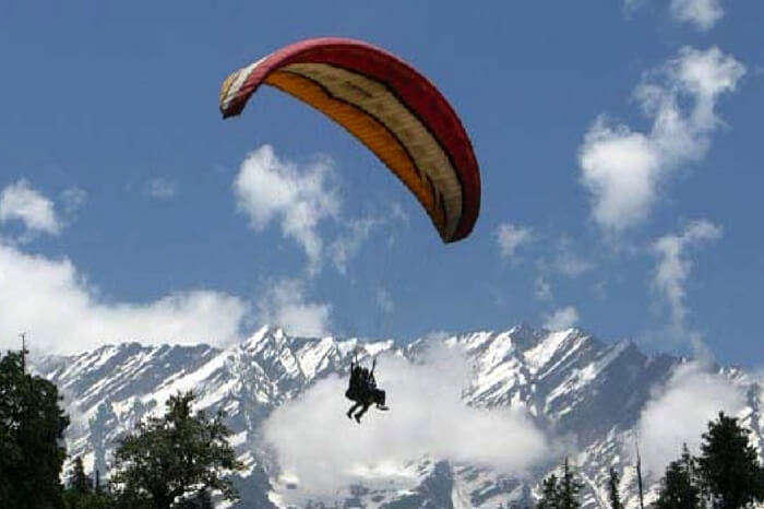 A traveler paragliding in Solang Valley in Manali