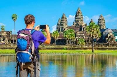 Young man taking a photo of Angkor Wat temple in Cambodia