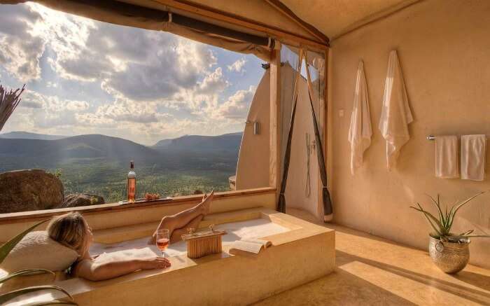 A woman enjoying a drink and scenery from her bathtub in Saruni Samburu in Kenya