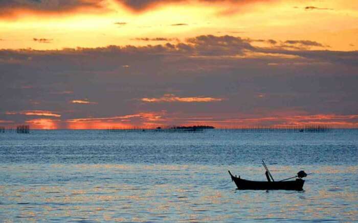 a boat against the orange sunset sky at Naklua beach