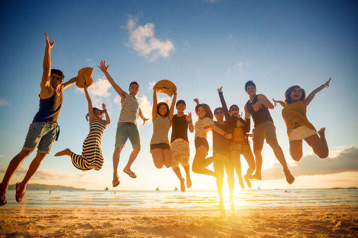 Group of young people jumping on beach